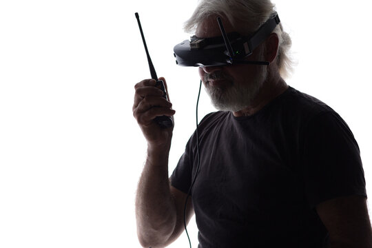 silhouette of bearded elderly man operating FPV drone in googles on his head and walkie-talkie, studio shot of modern human