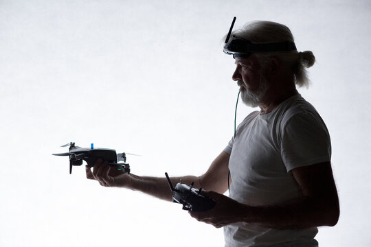 Silhouetted elderly man put a drone in his hand on studio background, modern hobby and technology, human tamed technologies
