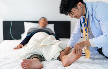 Fototapeta premium scene of doctor checking bedridden patient's foot. illness senior man with infectious disease. home caregiver nurse visit retire elderly people for health check up recovery process medical service