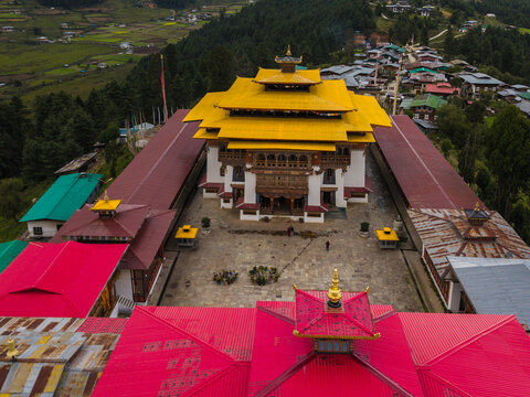 Aerial view of Gangtey Monastery with its vibrant gold roofs contrasted against the red and green structures nestled in the valley, Gangtey village, Wangdue Phodrang, Bhutan.