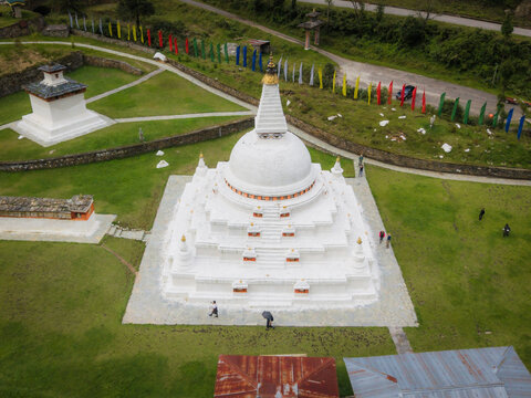 Aerial view of the gleaming white Chendebji Chorten Stupa rises majestically against the verdant landscape dotted with vibrant prayer flags, Chendebji village, Trongsa, Bhutan.