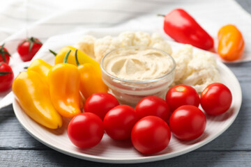 Different fresh vegetables and sauce on grey wooden table, closeup