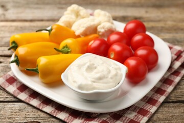 Different fresh vegetables and sauce on wooden table, closeup