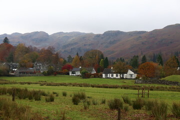 Elterwater Village on a still Autumn day. Low cloud limits the view but autumn colours adorn the trees in the village.