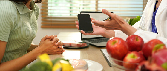 Nutrition and Wellness. A healthcare professional shows a smartphone with dietary advice alongside...