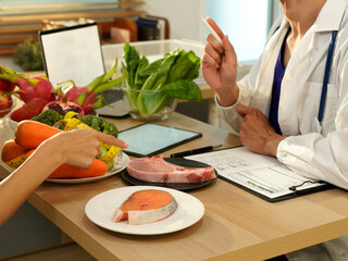 Dietician, male nutrition specialist consulting woman, developing healthy diet, dietary program. Dietary consultant asking, giving male patient advice, help, nutritional information, new meal plan