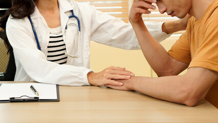 Fototapeta premium Doctor, patient and holding hands on desk in consultation room with support, empathy and announcement. Medic, person and care with comfort, diagnosis and helping with healthcare service at hospital