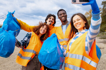 Diverse group of volunteers taking selfie while holding collected trash bags.