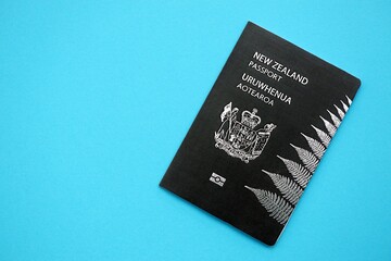 New Zealand black passport on light blue table background close up. Concept of travel and tourism