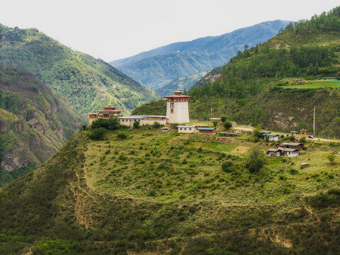 Aerial view of the majestic Raga Lhakhang perched atop a hill, embraced by verdant slopes, under a soft, diffused light, Raga, Paro, Bhutan.