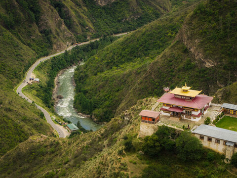 Aerial view of the temple complex nestled on the hillside, overlooking the flowing river and winding road, a serene blend of nature and architecture, Raga, Paro, Bhutan.