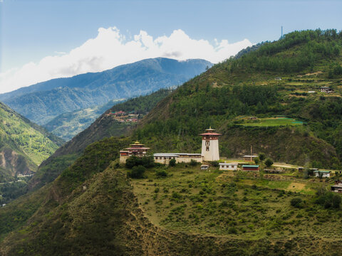 Aerial view of the majestic fortress-monastery perched atop the lush green hill, its white tower contrasting against the deep blue sky, Raga, Paro, Bhutan.