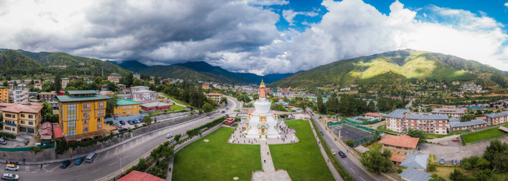 Aerial panoramic view of the Memorial Chorten stands tall amidst the city's green spaces, framed by the distant mountains and dramatic skies, Thimphu, Bhutan.