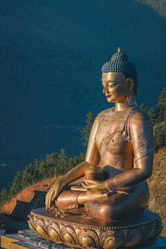 Aerial view of the golden Buddha Dordenma statue gleams against the backdrop of the mountainous landscape, bathed in the warm glow of the setting sun, Thimphu, Thimphu, Bhutan.