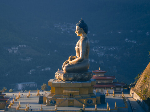 Aerial view of the colossal golden Buddha Dordenma statue perched serenely amidst the lush green hills and traditional architecture, Thimphu, Thimphu, Bhutan.