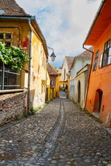 Cityscape. Old cobbled street with colorful buildings. Old town of Sighisoara, Transylvania, Romania
