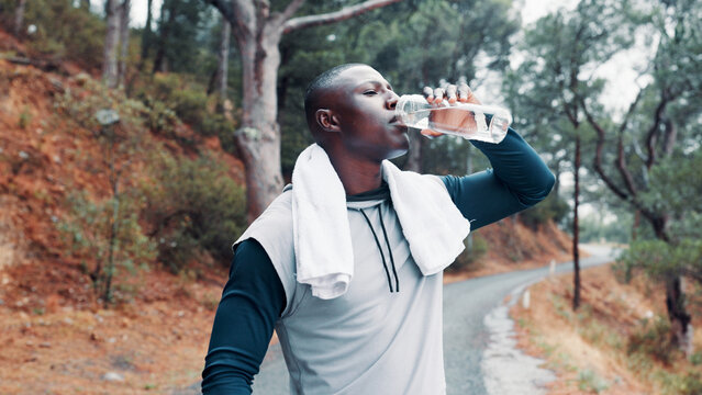 Fitness, black man and drink water in forest with towel for wellness, workout break and recovery. Active person outdoor, beverage and electrolytes in nature for exercise rest, hydration and thirst. - Powered by Adobe