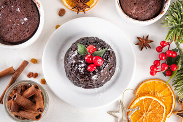 Traditional English Christmas pudding mug cake. Simple Christmas pudding recipe idea, made on tea mug with microwave, portioned Christmas pudding with sugar powder and cranberry festive decor