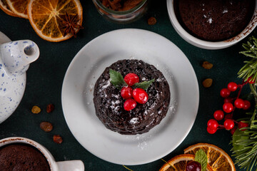 Traditional English Christmas pudding mug cake. Simple Christmas pudding recipe idea, made on tea mug with microwave, portioned Christmas pudding with sugar powder and cranberry festive decor