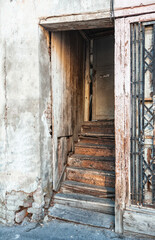 Abandoned entrance with worn wooden stairs shows rustic decay