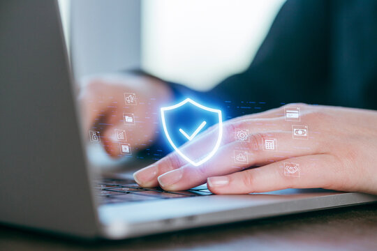 Hand typing on laptop with digital security symbols appearing, representing online safety and protection