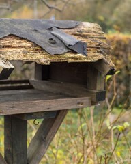 Old wooden birdhouse with damaged roof needs repair in garden