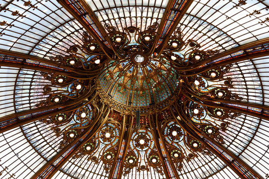 Low angle intricate details of the center of the famous 1912 stained glass Art Nouveau dome in the Galeries Lafayette main historic store, Paris, France