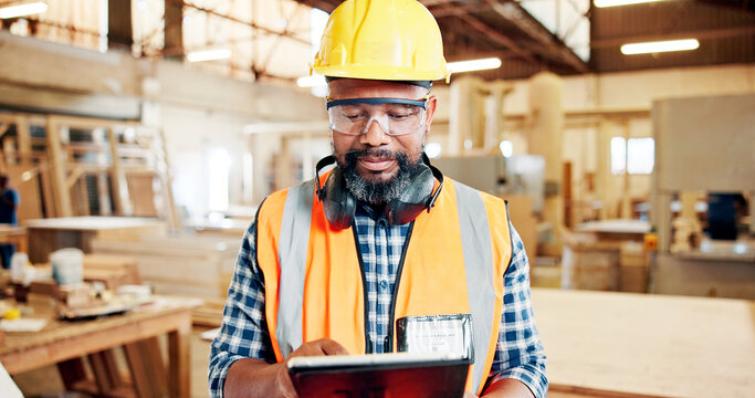 Tablet, black man and woodworker in workshop for furniture manufacturing, design or production. Digital technology, safety gear and African mature carpenter with research for lumber quality assurance