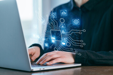 Working on a laptop with digital technology icons in a modern office setting during daytime