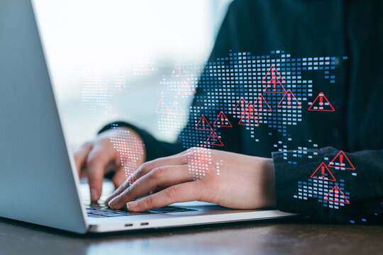 Person working on laptop with digital security alerts displayed on screen, emphasizing technology and data concerns in a modern workspace