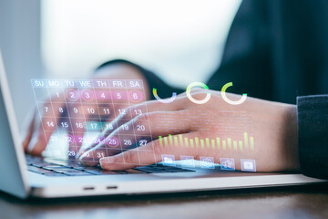 Hands working on laptop displaying digital calendar and analytics in a bright indoor space