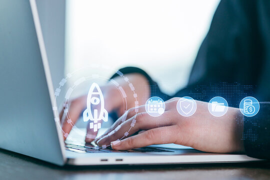Hands typing on a laptop with icons illustrating digital progress and innovation in a bright, modern workspace