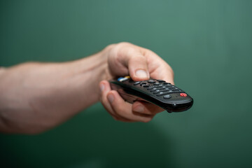 Hand Holding Remote Control Against Green Background