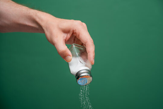 Hand Shaking Salt From A Shaker Green Background - Powered by Adobe