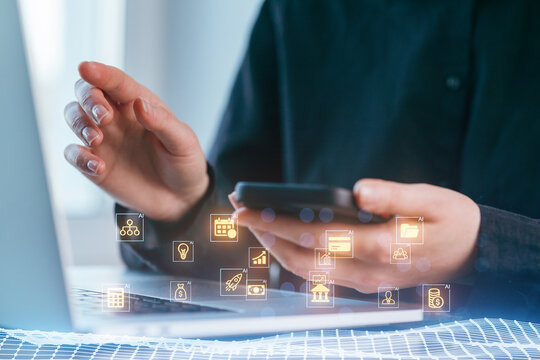 Person using smartphone and laptop for digital communication in a modern workspace