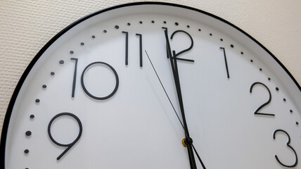 Fototapeta premium Simple white round clock displaying almost noon