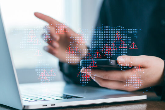 Digital security work being done at a desk with a laptop and smartphone displaying alerts in a home office environment - Powered by Adobe