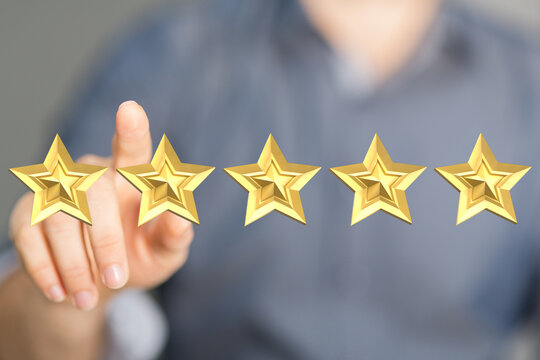 A person's finger touching five golden stars, conveying a sense of achievement, excellent rating, and customer satisfaction. Suitable for review