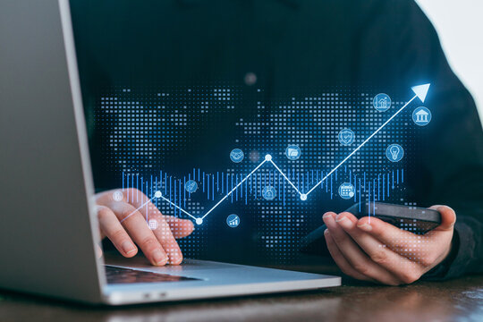 Professional working on financial analysis using laptop and smartphone in a modern office setting