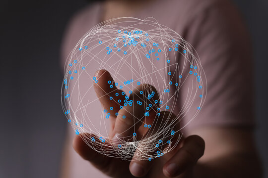 Person holding a globe made of lines and dots symbolizing global connection and network technology. Represents the concept of digital