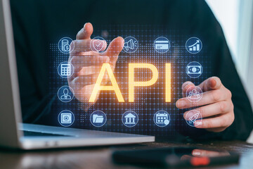 Hands demonstrating API integration on a laptop with digital icons representing data and technology