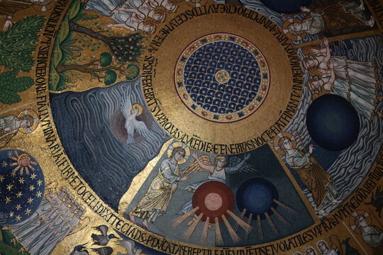 Golden mosaic ceiling inside St. Mark&rsquo;s Basilica in Venice, Italy, depicting scenes from the Creation with angels, stars, and Latin inscriptions in Byzantine style.