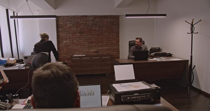 Multigenerational business associates collaborate on a project, reviewing data and discussing strategies in a modern office setting.