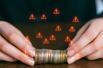 Hands holding coins with warning signs in a financial setting during the day