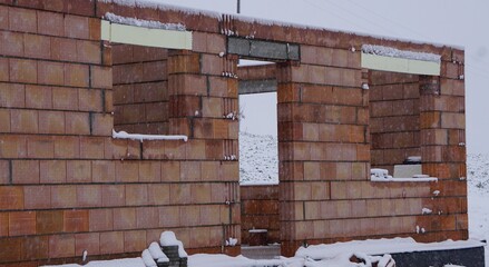 Front domu w trakcie murowania, ściana z cegieł pokazuje etap budowy. Surowa konstrukcja przygotowuje fundamenty przyszłego wnętrza. © Adam