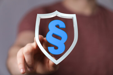 A visual representation of legal protection, featuring a person's hand holding a shield with a...