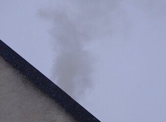 Dym unoszący się nad dachem domu w zimowy dzień, tworzący smog. W powietrzu mogą znajdować się szkodliwe związki, m.in. benzopiren, podkreślając problem zanieczyszczenia powietrza.