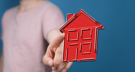 A hand presents a house icon, representing real estate, home ownership, and the concept of...