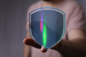 Person holding a digital shield with glowing elements symbolizing online protection and data security. Perfect for illustrating cyber