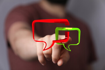 Man touching two speech bubbles in a virtual overlay, depicting online chat and communication concept with digital interface.